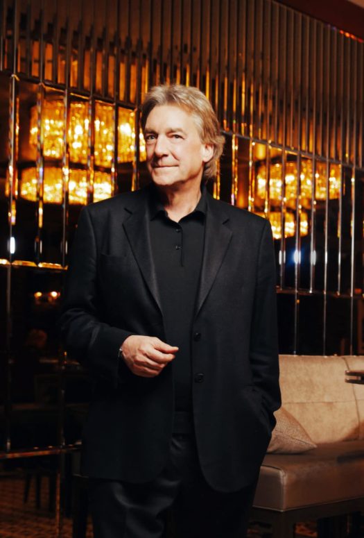Headshot of Jeffrey Beers in a wine bar. Bronze walls in the background, with booth seating and a wine rack to his left.