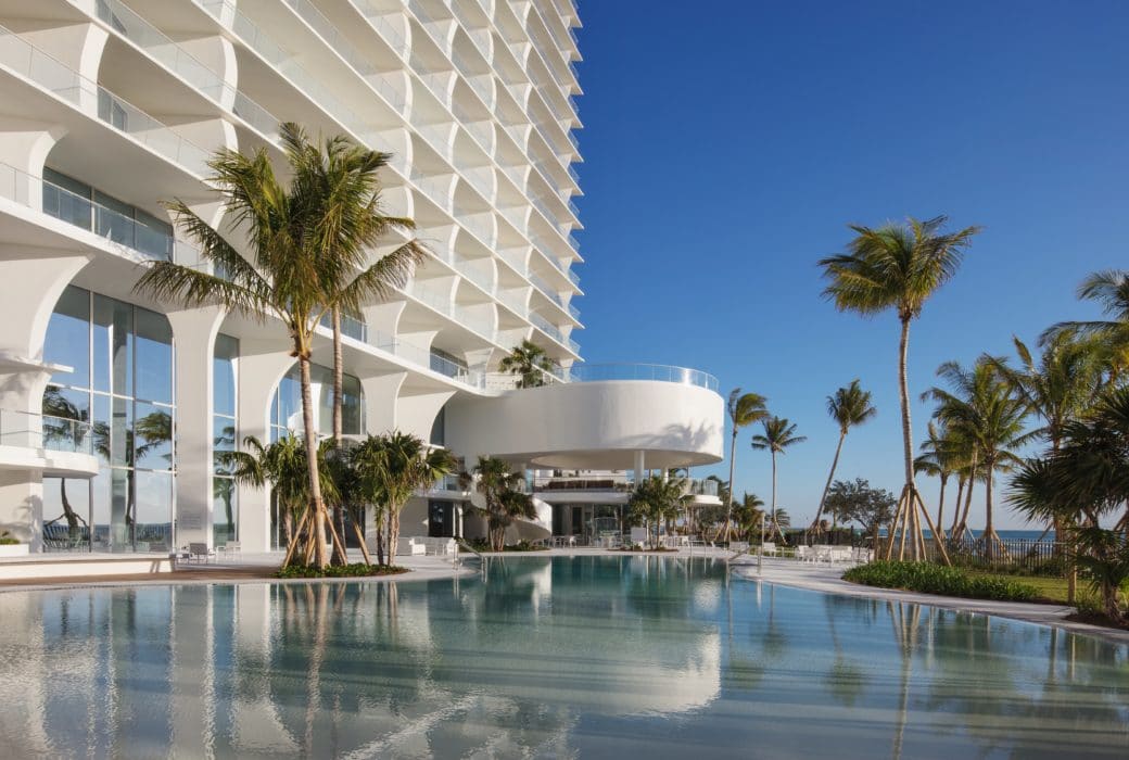 Exterior view of Jade Signature condominiums pool, bar and grill area. Has oceanfront view with palm trees surrounding.