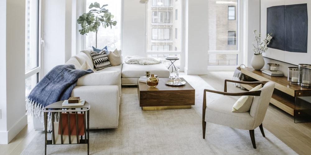 Living room at The Park Loggia luxury condominiums in New York. Corner room with white walls, tall windows, and furniture.
