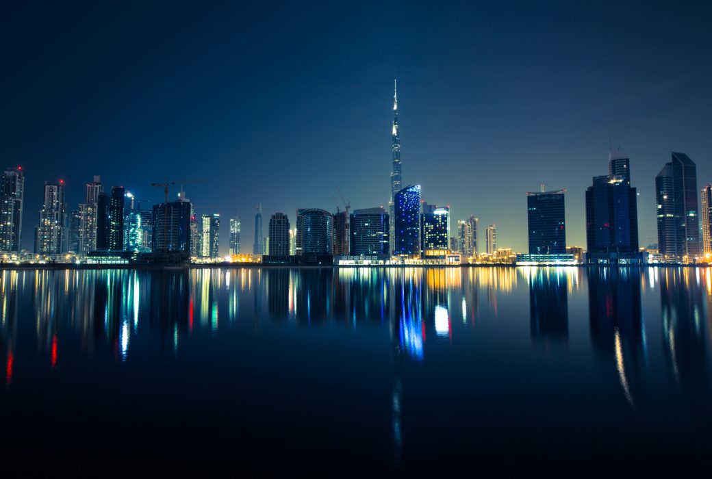 City skyline of Dubai at night. Picture taken from the water looking at the dark with with high rises along the waterfront.