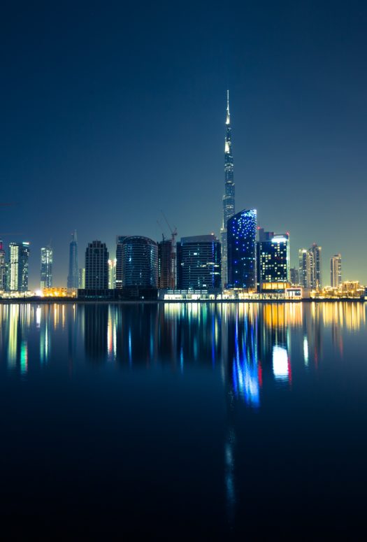 City skyline of Dubai at night. Picture taken from the water looking at the dark with with high rises along the waterfront.
