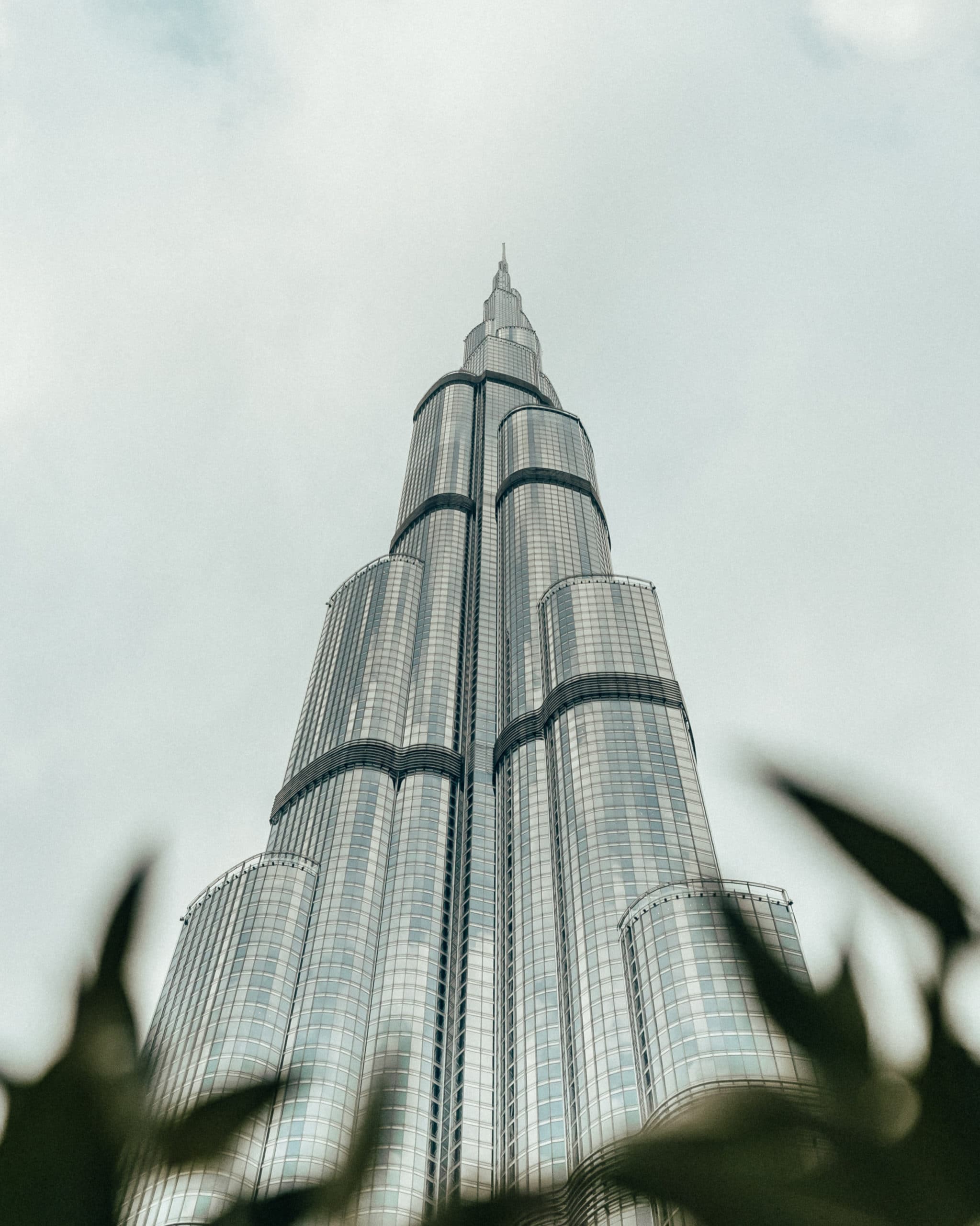 Rendering of skyscraper with glass facade and cylindrical features climbing into the clouds.