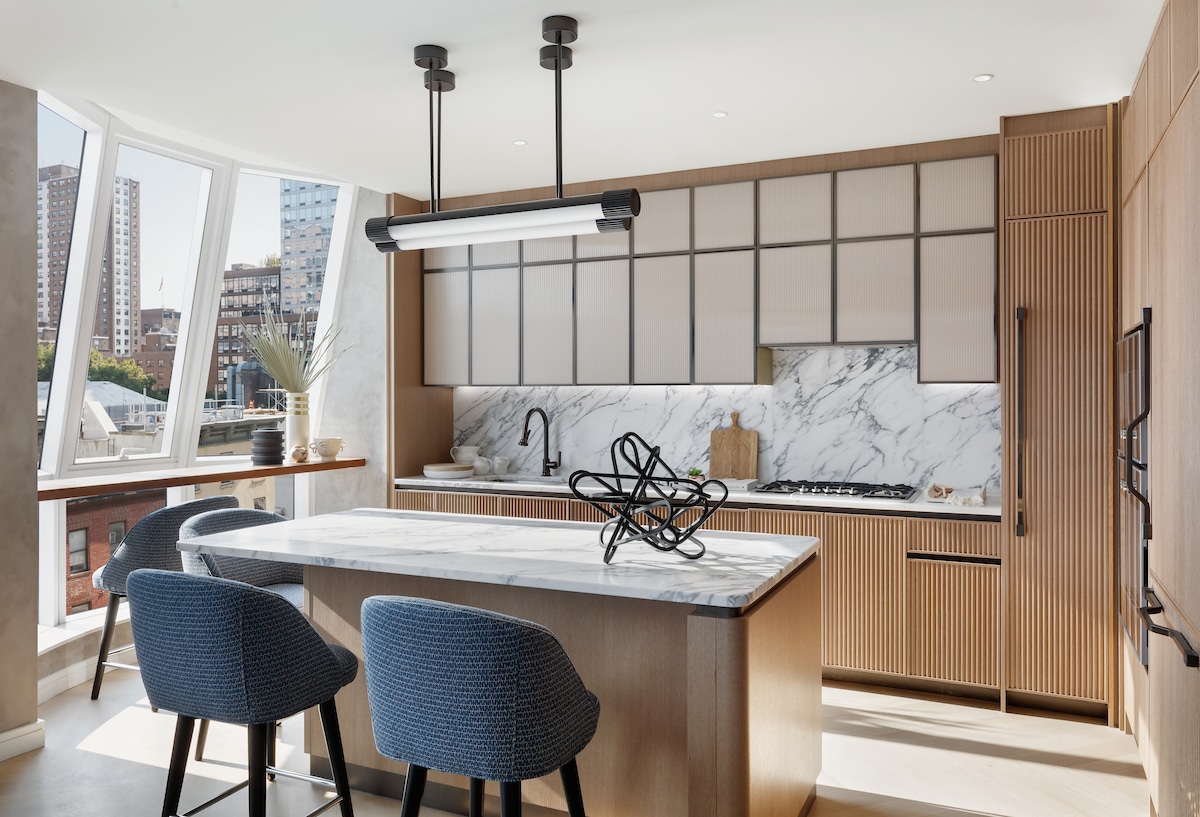 Kitchen at Lantern House luxury condos in New York. Natural wood finishes, white stone countertops and large windows.