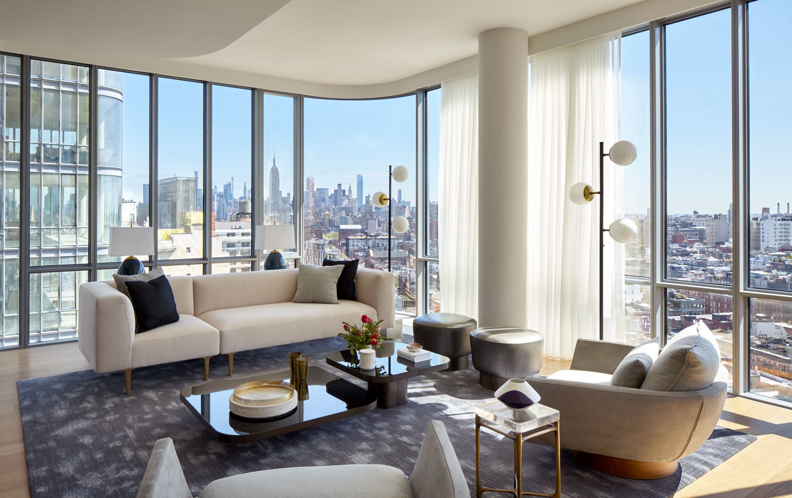 Interior view of 565 Broome residence living room with window view of New York City. Has full furniture and white walls.