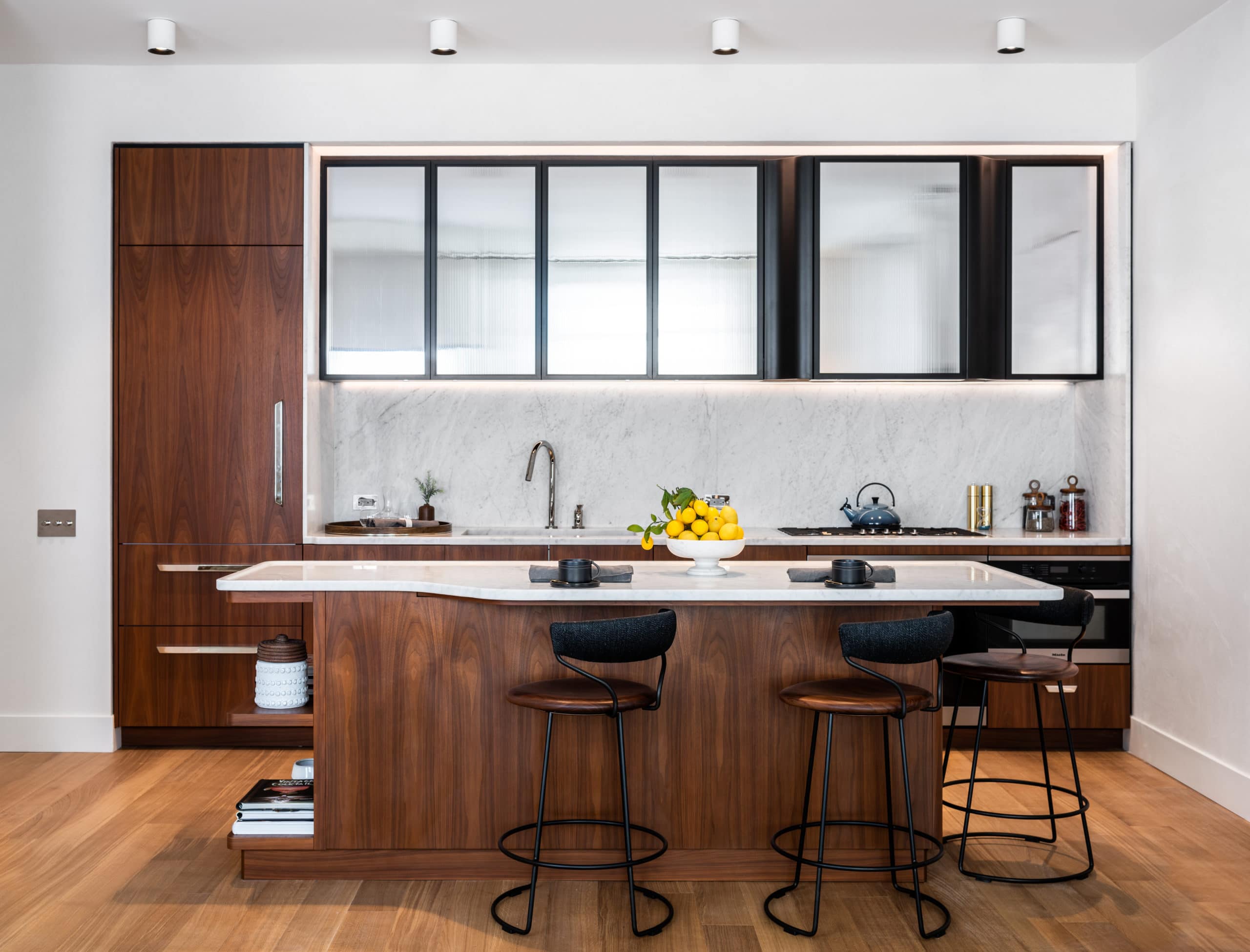 Kitchen in Greenwich West luxury condos in New York. Center island, stone countertops, white backsplash and glass cabinets.