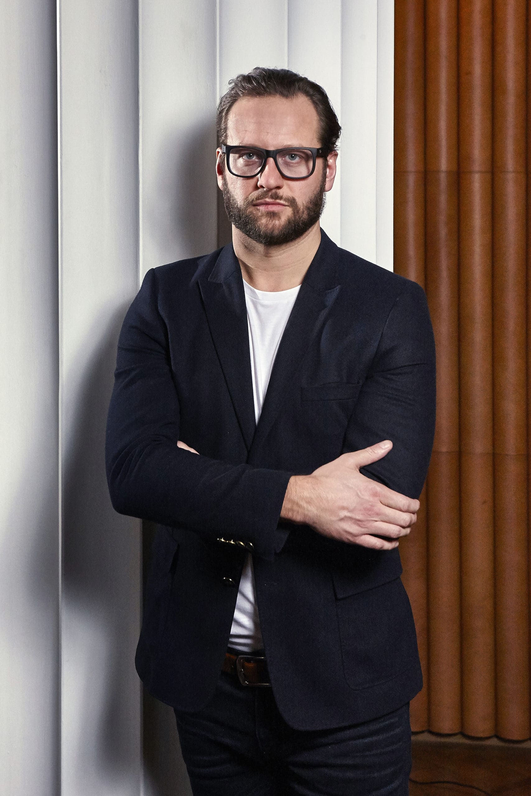 Profile picture of Elliot March standing with his arms crossed. Man wearing glasses, navy suit jacket, and white T-shirt.