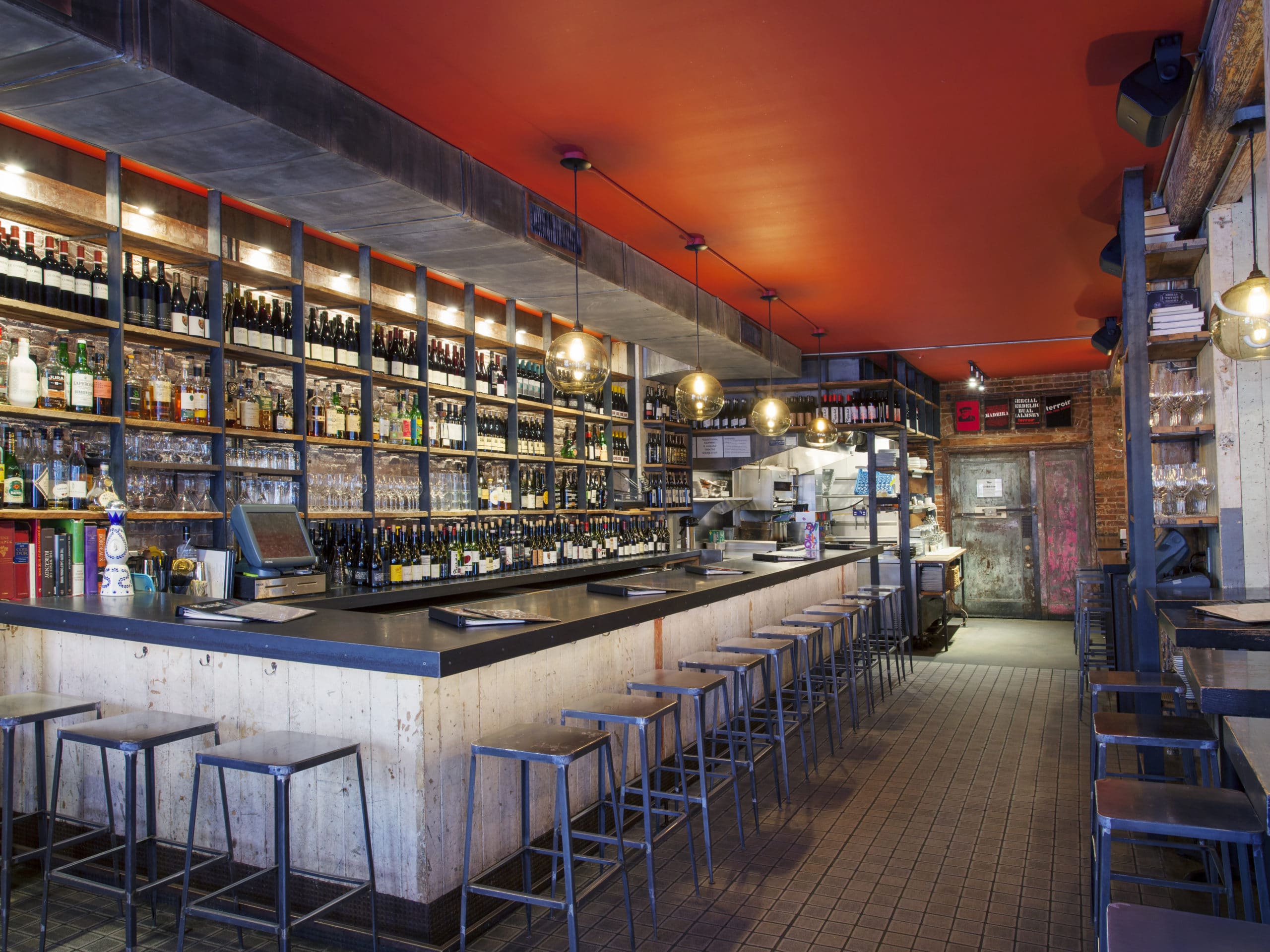 Residents wine bar at 30 Warren luxury residences in NYC. L-shaped bar with stools and wine bottles on the back shelves.